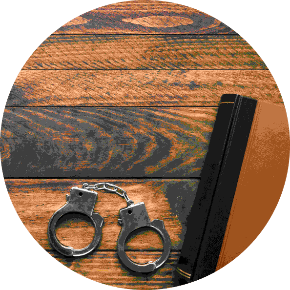 A book, handcuffs, and a pen arranged on a wooden table, suggesting themes of law or crime.